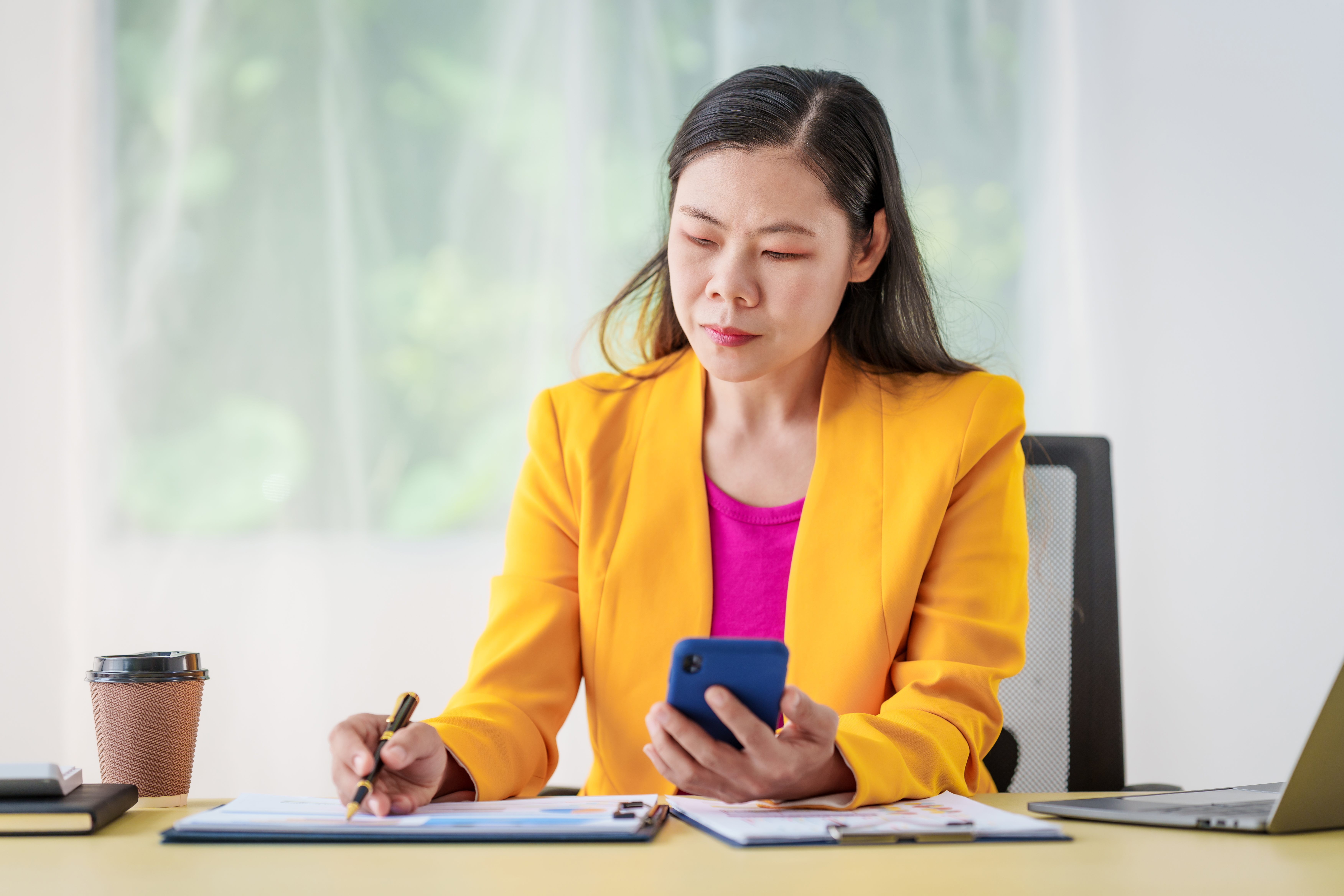 Investor at desk considers phone and papers.jpg